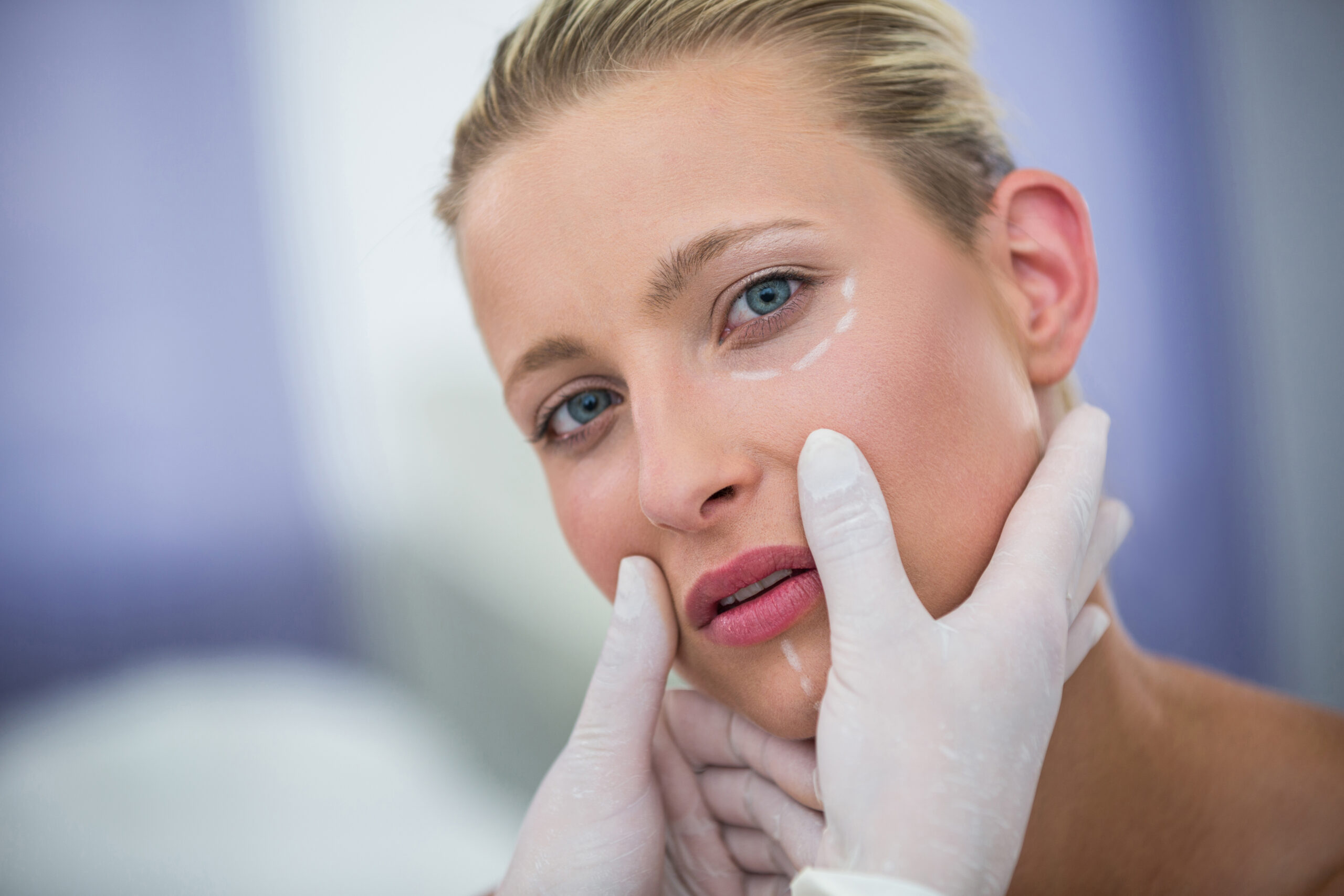 Close-up of doctor examining female patients face for cosmetic treatment